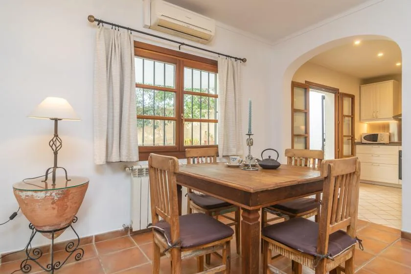 A dining area with a wooden table and chairs beside a window.