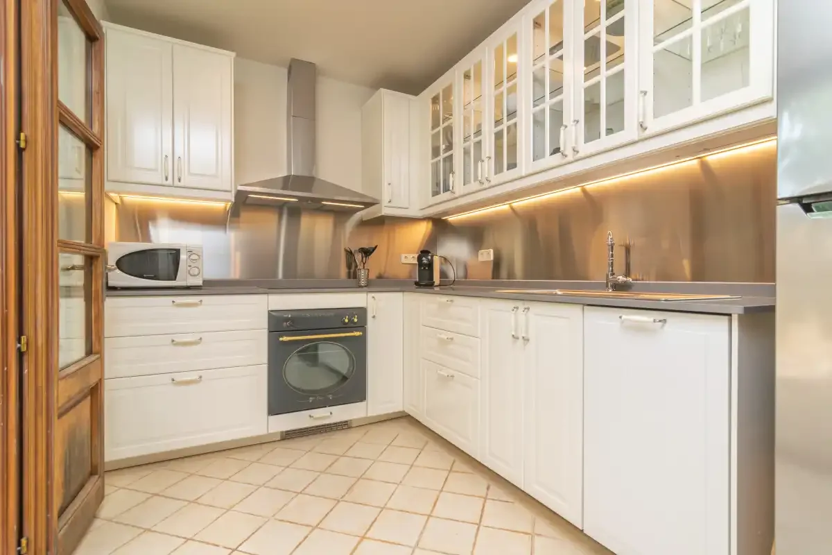 A bright kitchen with white cabinets and a tiled floor.