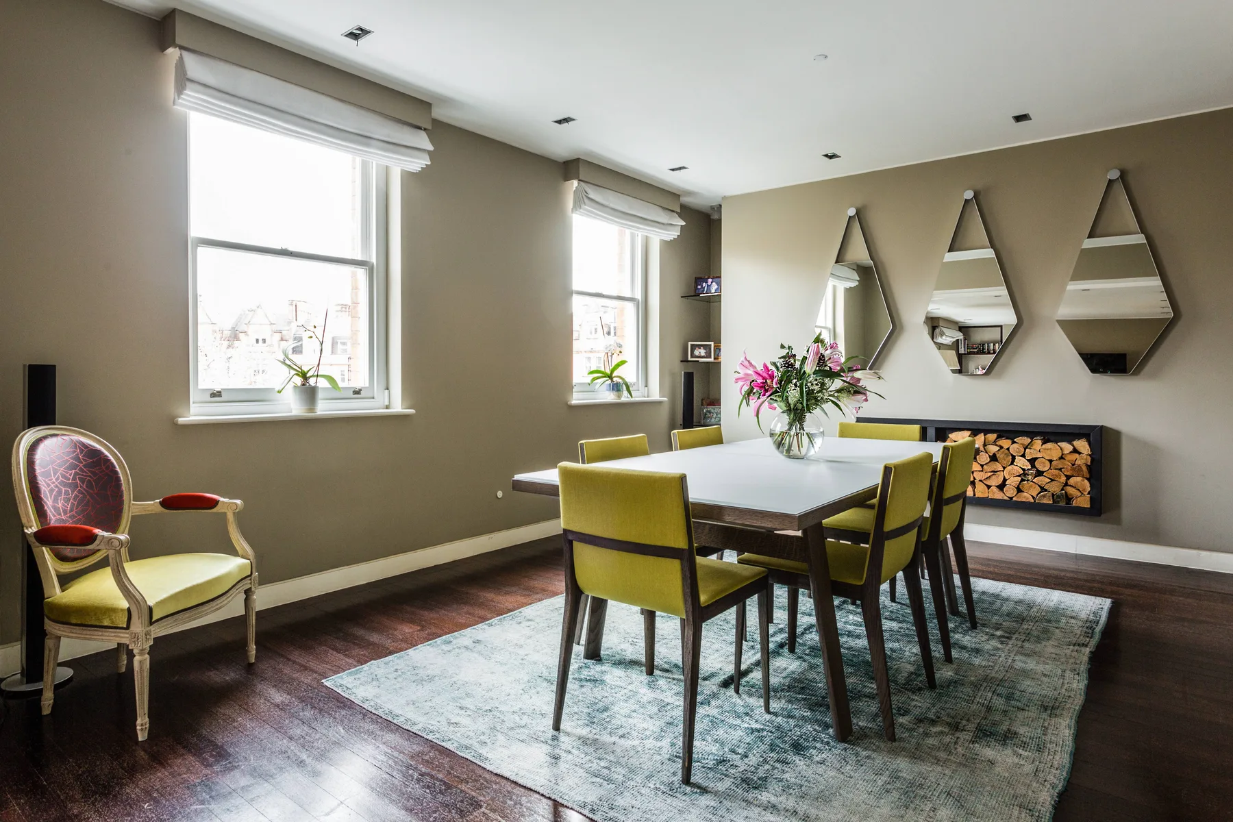 A dining area with a table and chairs beside windows and a fireplace.