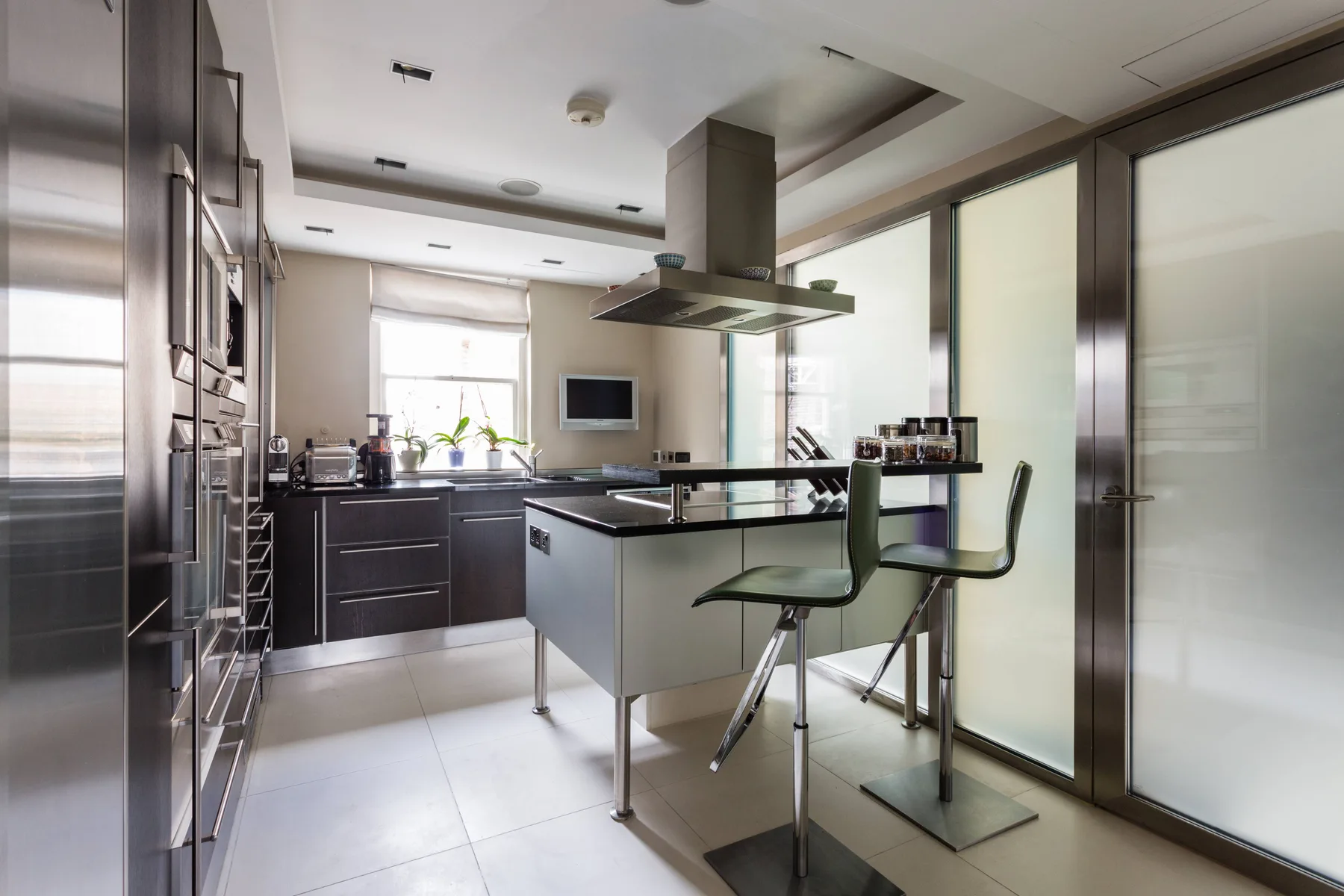 A modern kitchen with dark cabinets, a central island, and bar seating.