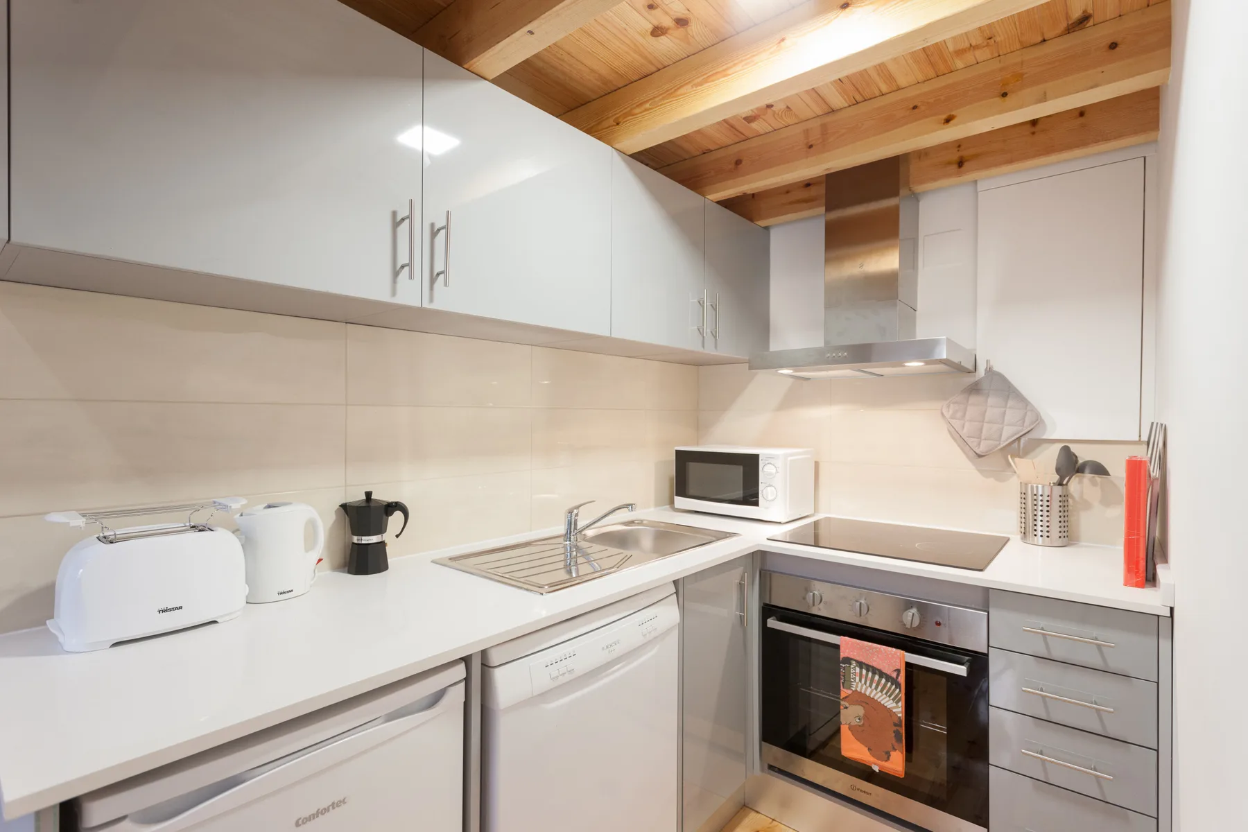 Una cocina compacta con gabinetes blancos, una encimera y electrodomésticos integrados.