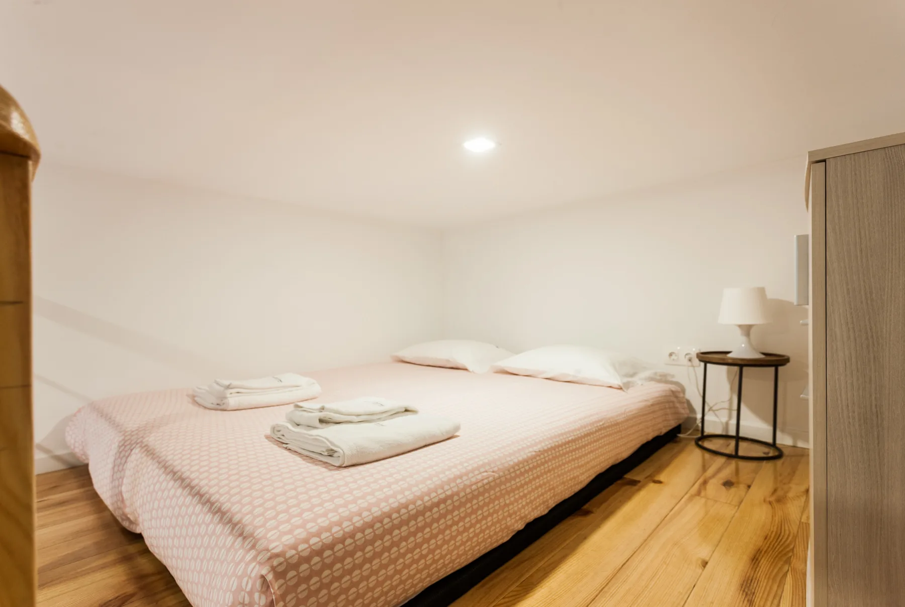 Un dormitorio con una cama bien hecha y una mesita de noche.