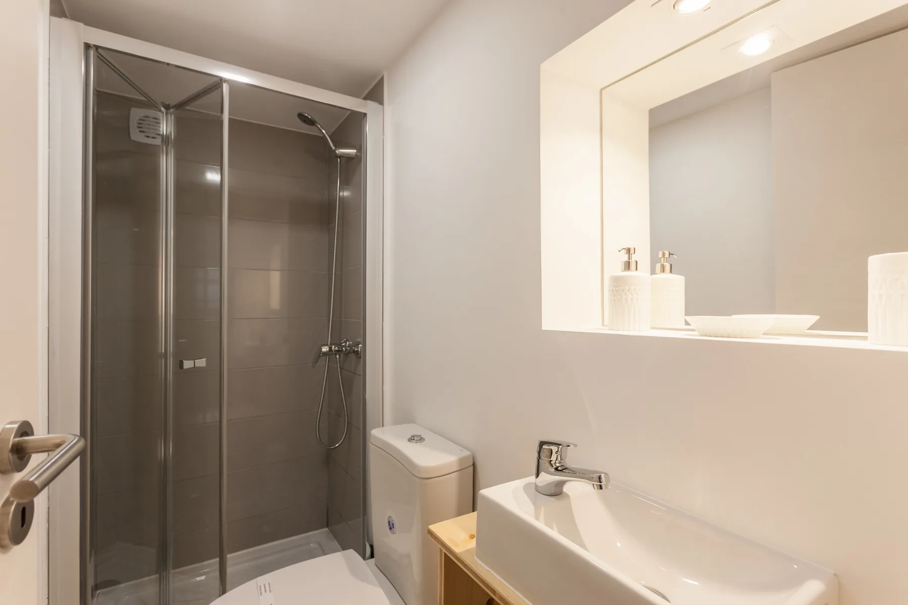 A bathroom with a glass-enclosed shower and a sink beneath a large mirror.