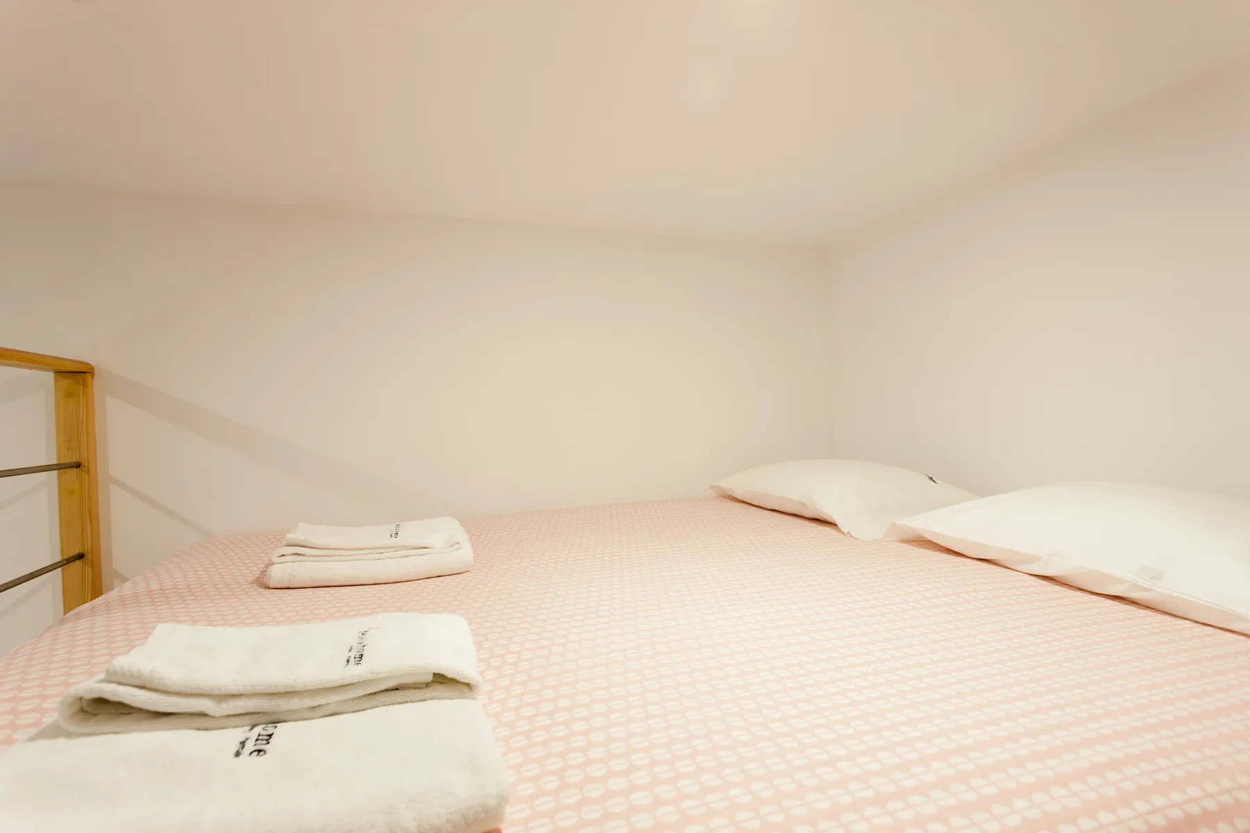 Una cama con toallas dobladas y almohadas en un dormitorio sencillo.