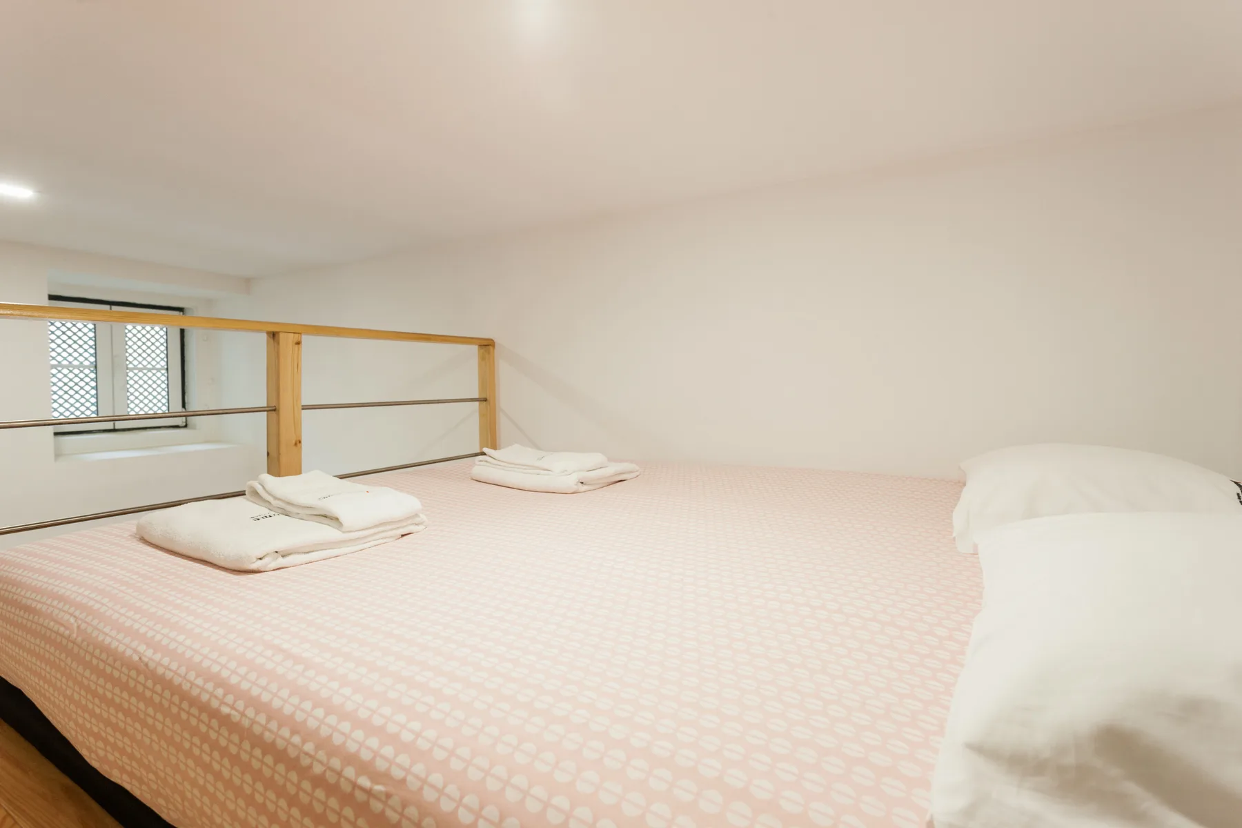 Un dormitorio luminoso con una cama estampada y una ventana pequeña.