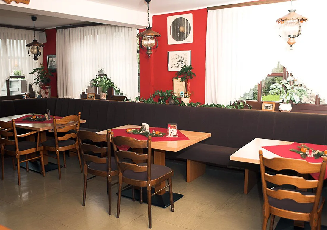 Comedor de la casa de huéspedes con paredes rojas y mesas de madera