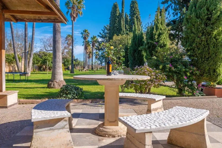 A landscaped garden patio with a round table and curved stone benches.