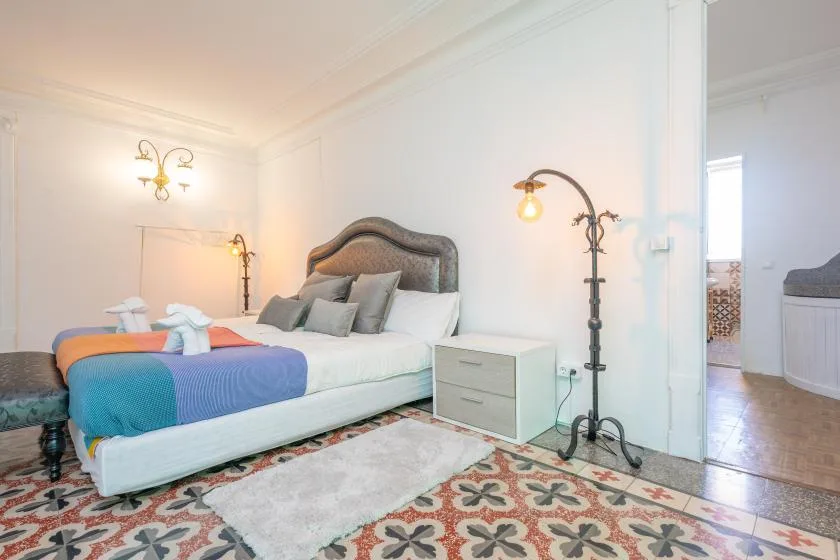 A bedroom with a bed, bedside table, and patterned floor tiles.