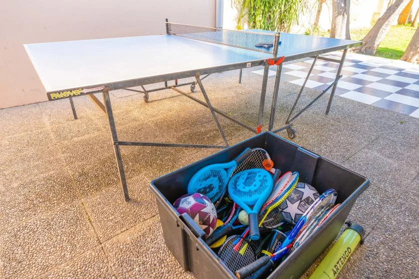 A table tennis setup with a box of paddles and other sports equipment.