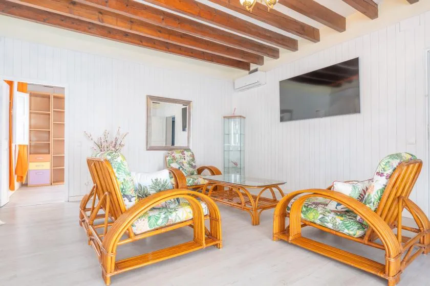 A bright living room with rattan seating arranged around a glass coffee table.