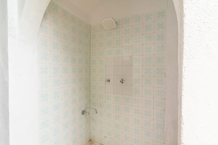 A tiled shower alcove with a wall-mounted showerhead and controls.