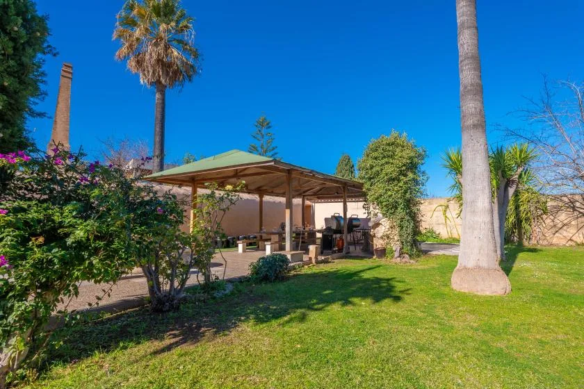 A garden patio with a shaded seating area and green lawn.