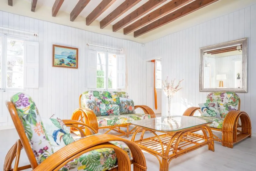 A bright living room with floral seating and a glass-topped wicker table.