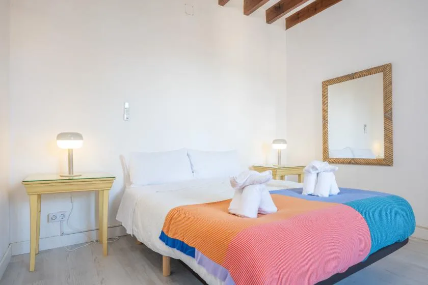 A bedroom with a bed covered in colorful bedding and bedside tables.