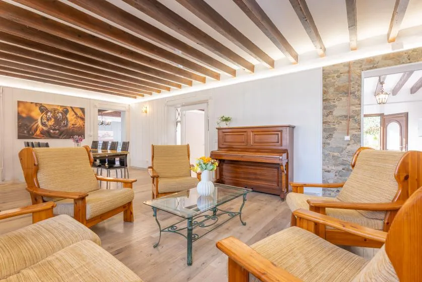 A bright living room with wooden seating and a piano.