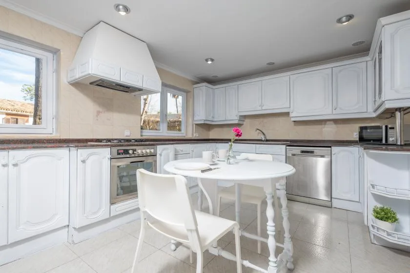A bright kitchen with white cabinetry and a round dining table.