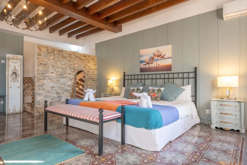 A bedroom with two beds, colorful bedding, and exposed wooden ceiling beams.