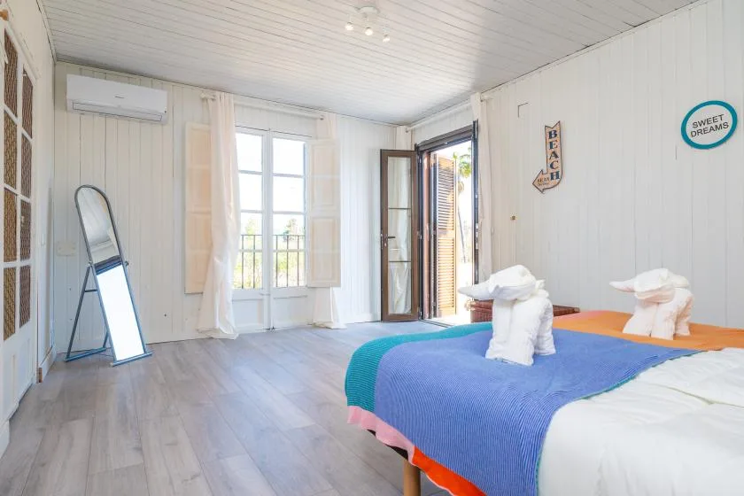 A bright bedroom with colorful bedding and an open doorway.
