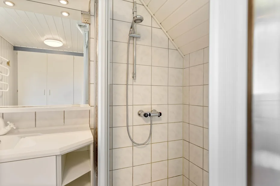 A tiled bathroom shower beside a sink and vanity.