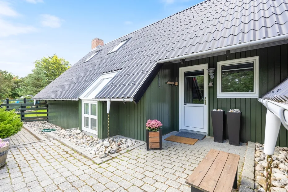 A dark green house exterior with a paved patio and front entrance.