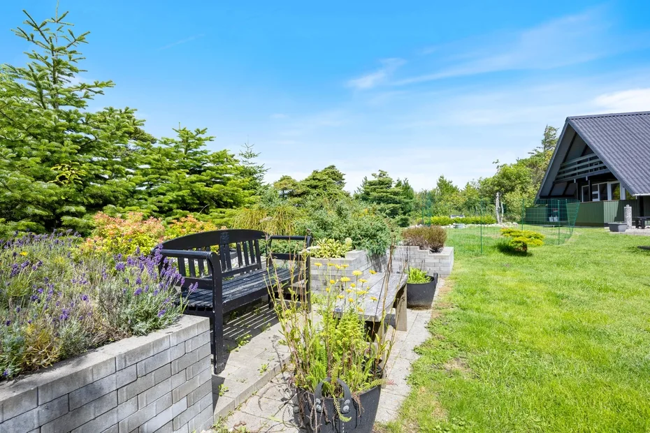 A garden seating area with a black bench, raised planters, and a lawn.