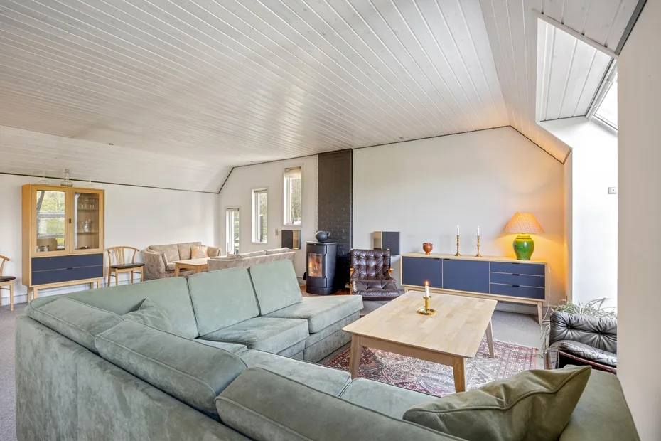 A bright living room with pale seating, a coffee table, and a wood-burning stove.