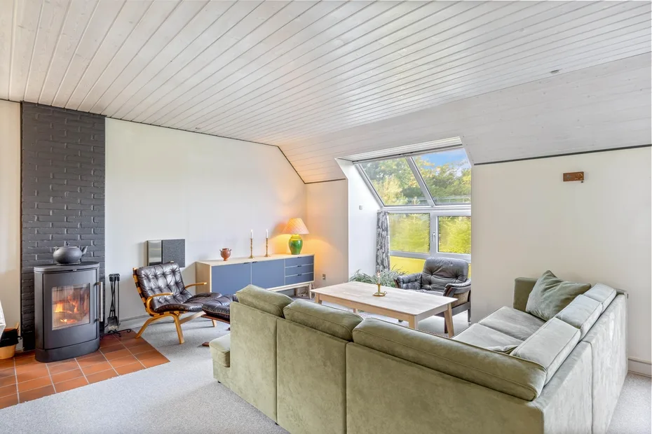A bright living room with a sectional seating area and a wood-burning stove.
