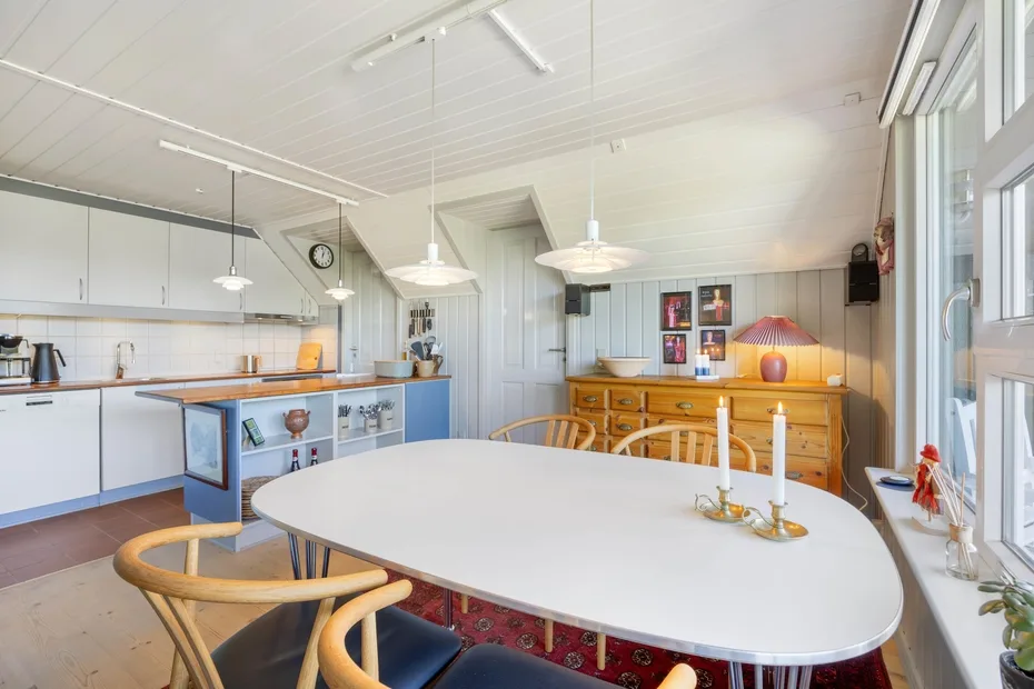 A bright kitchen and dining area with a large oval table and white cabinetry.