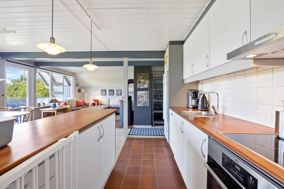 A bright kitchen with long countertops and a dining area by the windows.