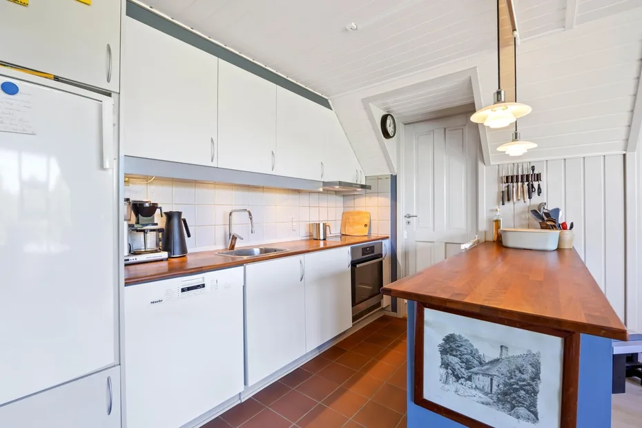 A bright kitchen with white cabinets and a long wooden island.