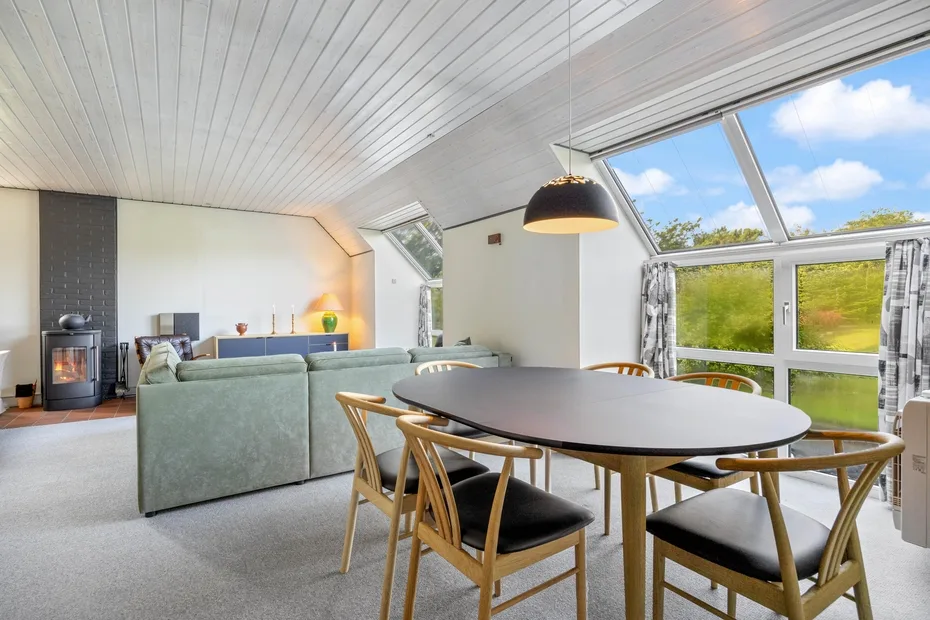 A bright open-plan living and dining area with large windows overlooking greenery.
