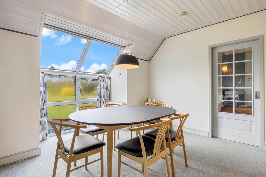A bright dining area with a table and chairs beside large windows.