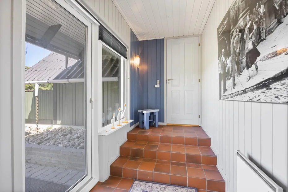 A bright entryway with terracotta tile steps leading to a white door.