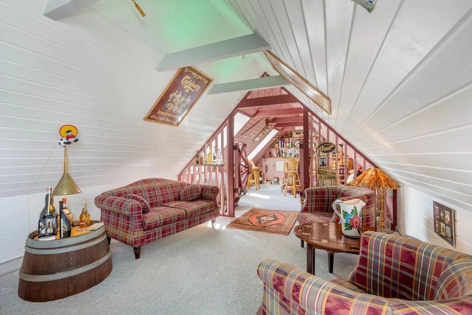A furnished attic lounge with plaid seating and a small round table.