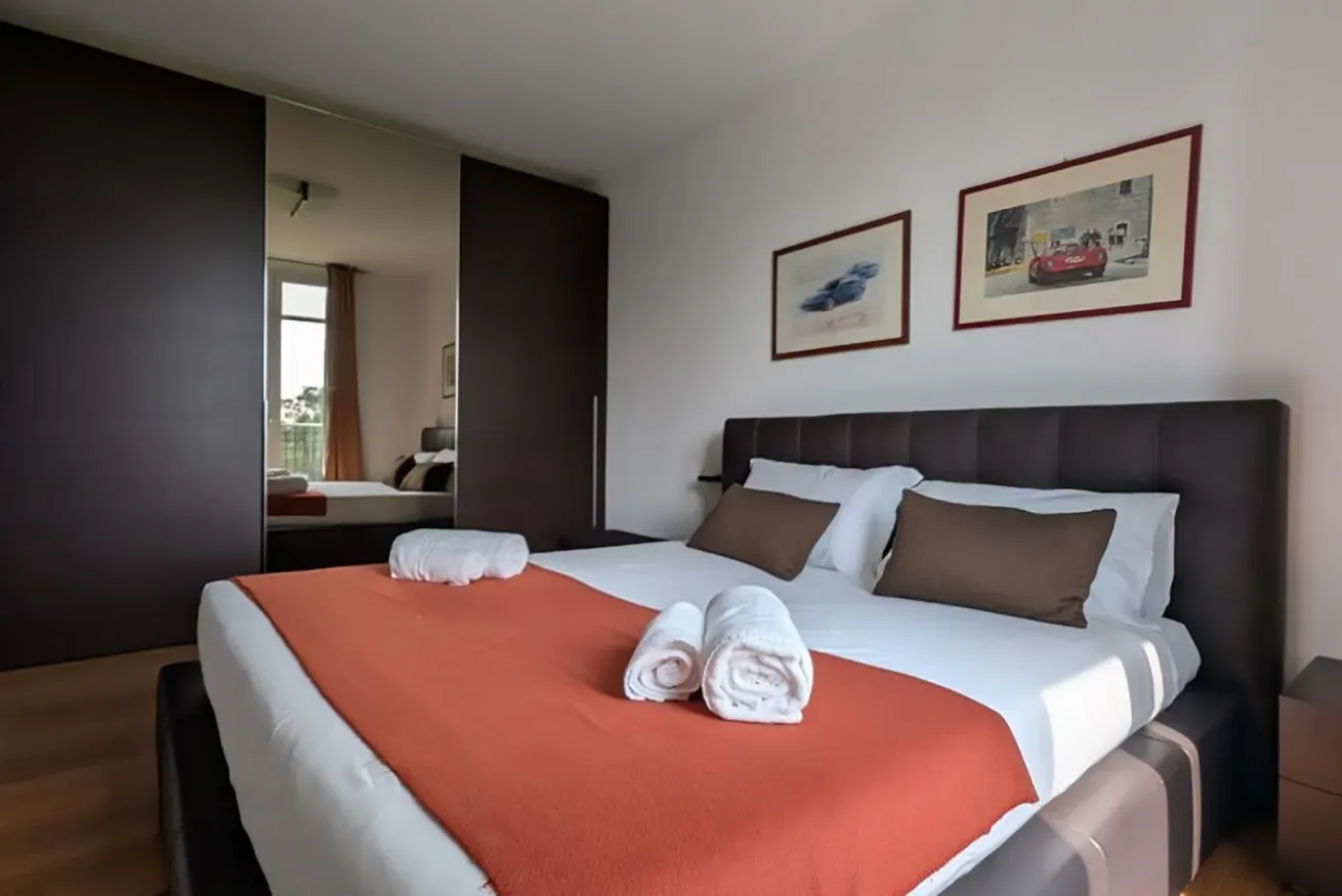 Un dormitorio con una cama bien tendida y cuadros enmarcados sobre el cabecero.