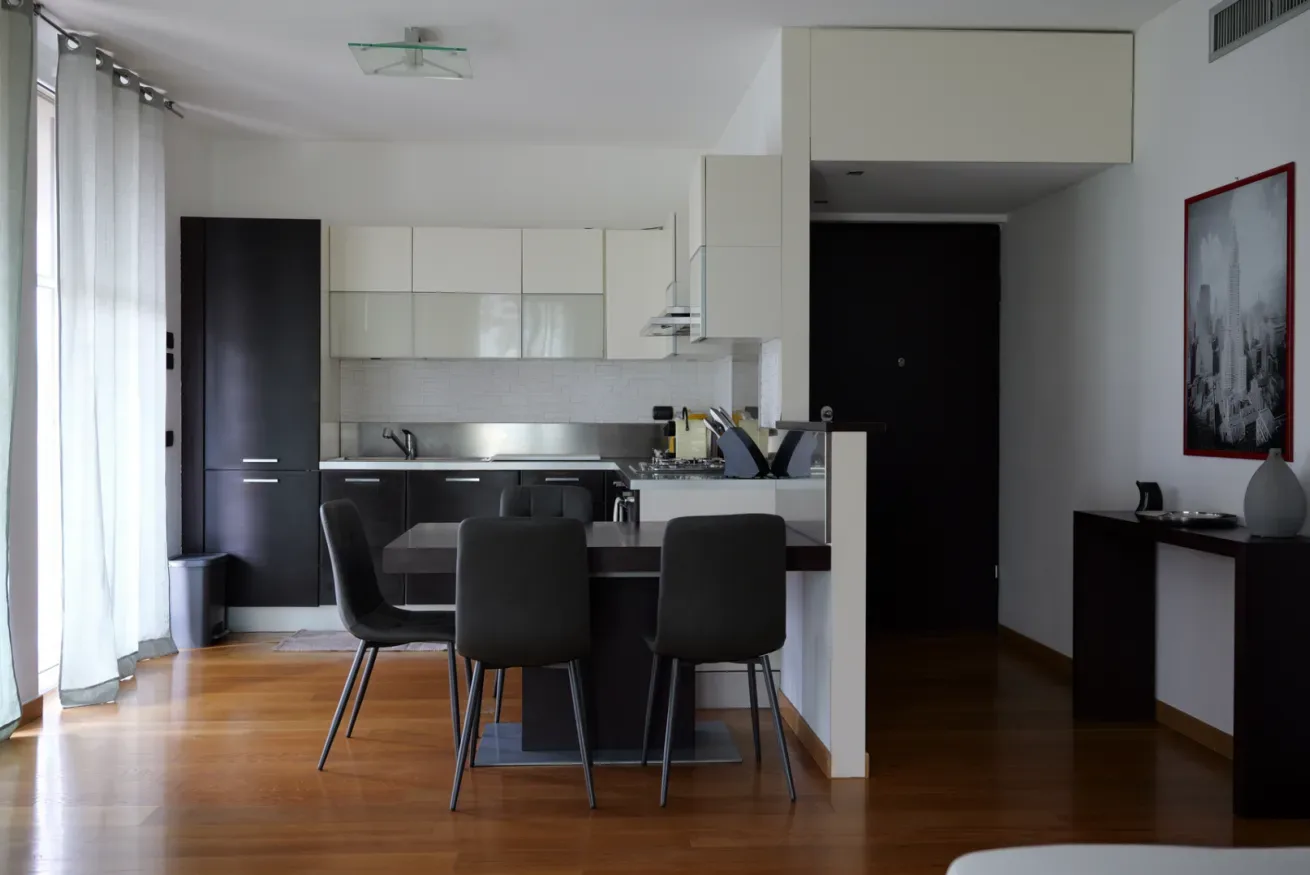 Una cocina moderna con comedor, muebles blancos y una mesa.