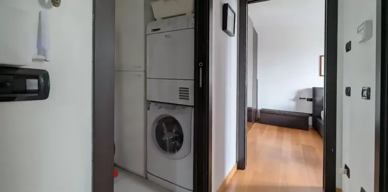 Un pasillo da a un dormitorio con suelo de madera y una cama.