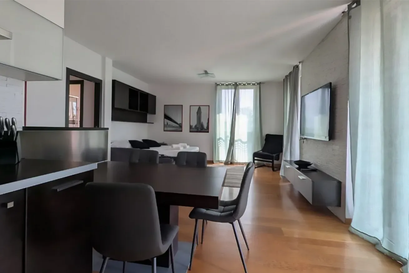 Una sala de estar y comedor moderna con mesa, asientos y ventanales.