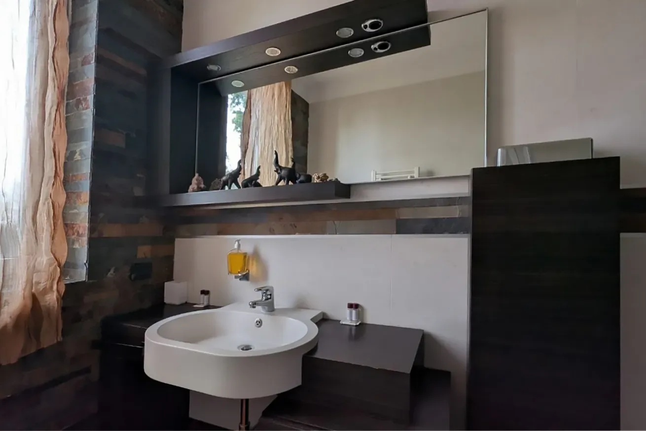 Un baño moderno con un lavabo suspendido debajo de un espejo grande.
