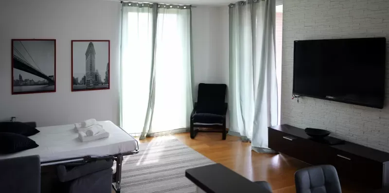 Un dormitorio con una cama, una silla y un televisor en la pared.
