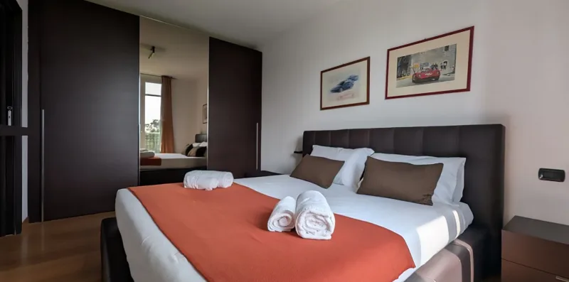 A bedroom with a neatly made bed and framed artwork on the wall.