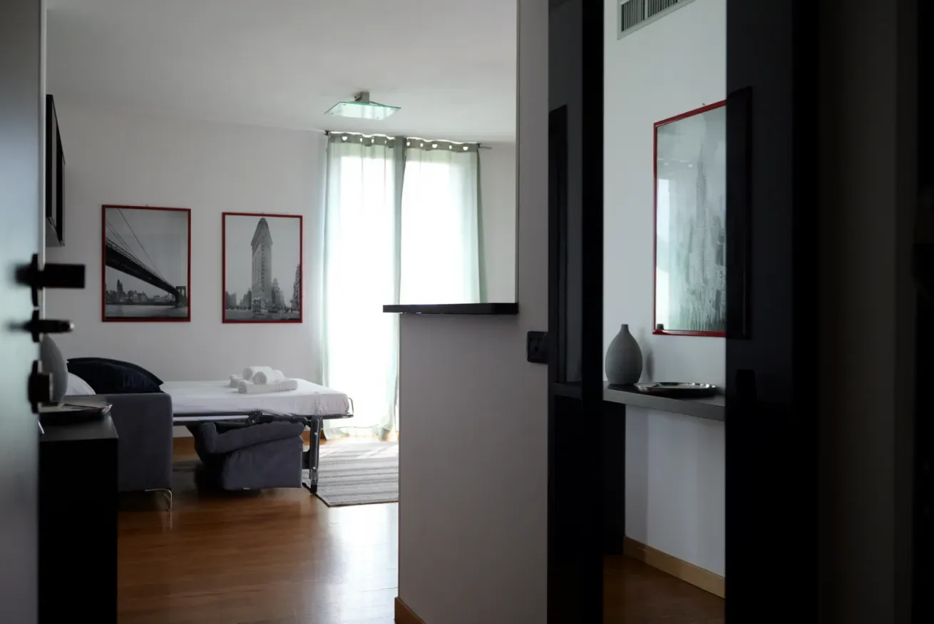 Un dormitorio con una cama, cuadros enmarcados y una ventana luminosa.
