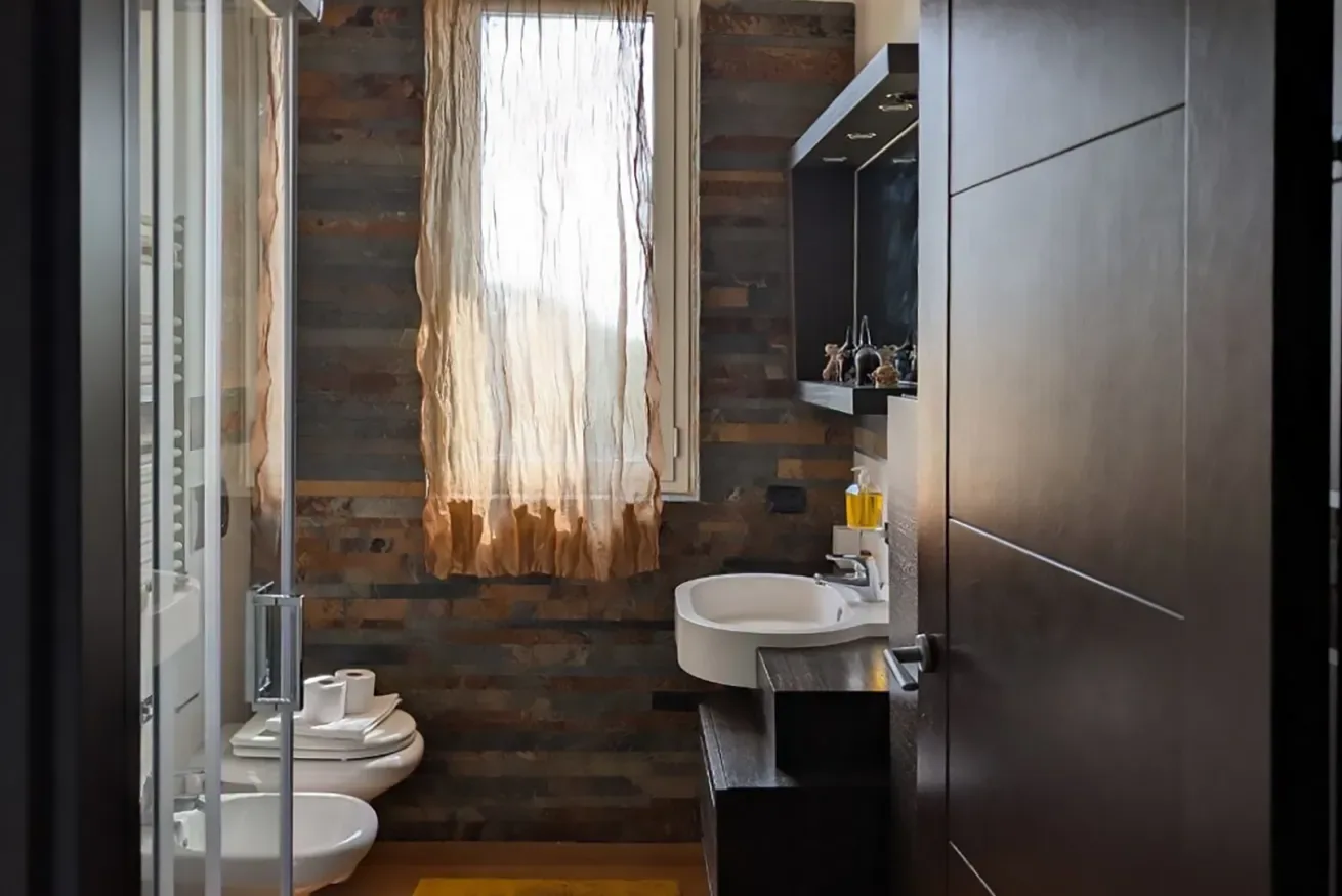 Un baño con lavabo, inodoro y una ventana con cortina.