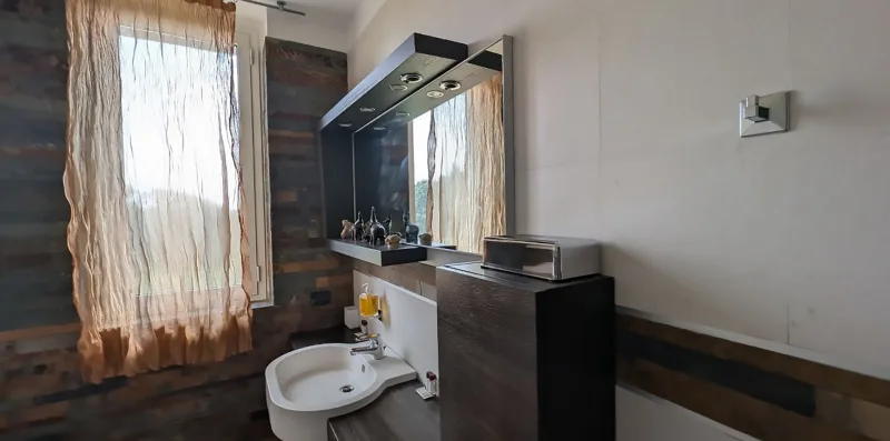 Un baño con lavabo, espejo y ventana.