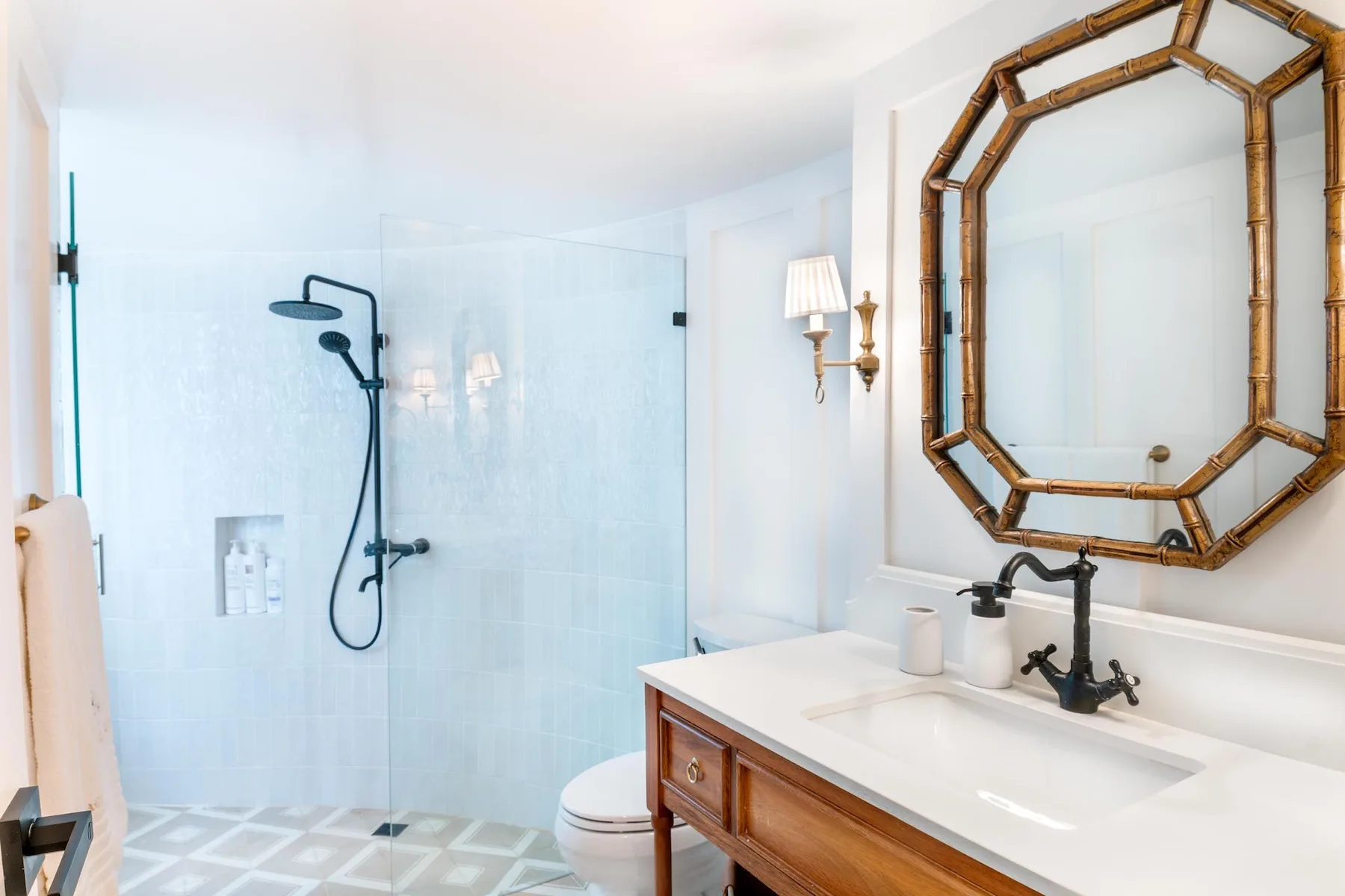 A bright bathroom with a glass shower and a vanity beneath a large mirror.