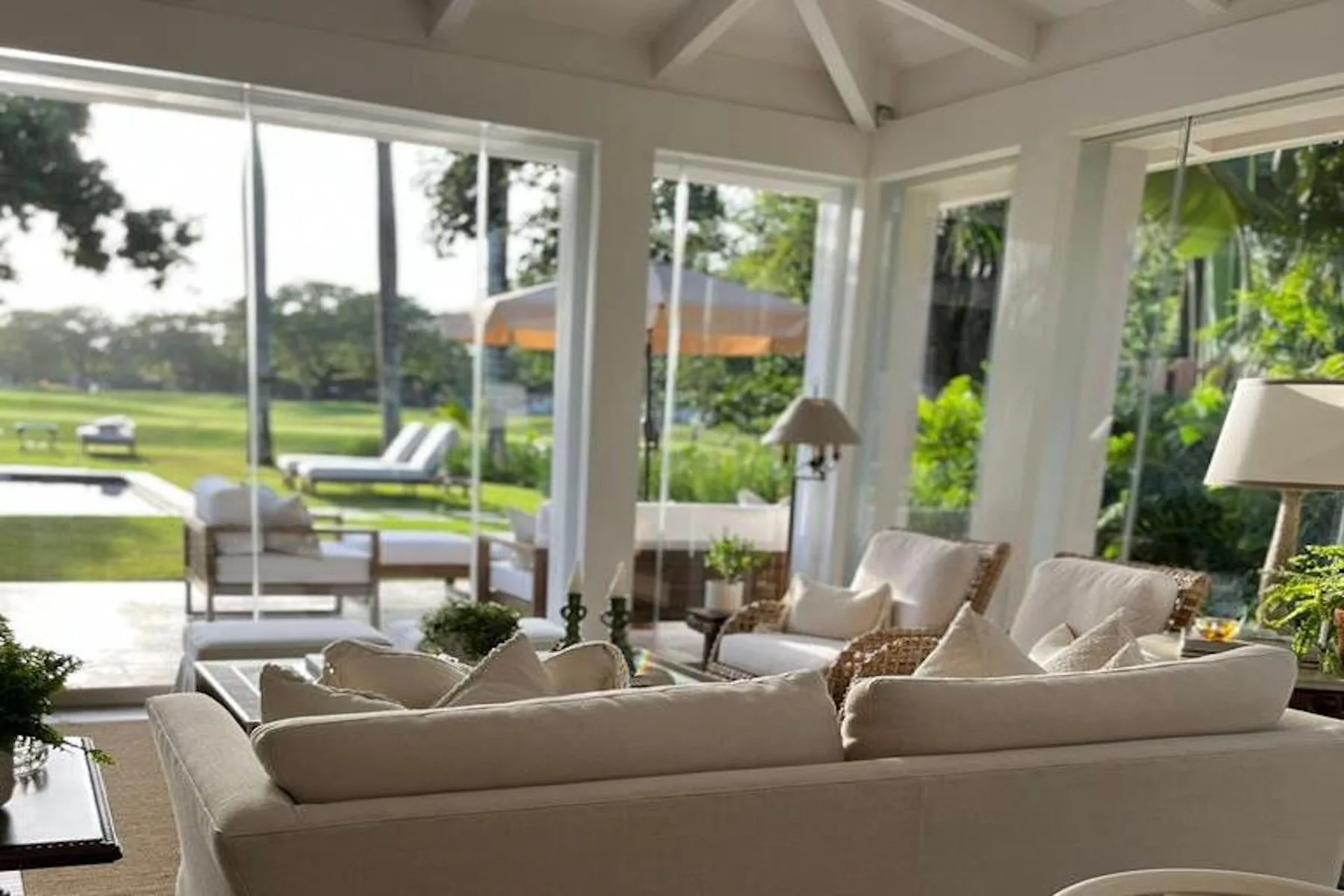 A bright living room with seating and large windows overlooking a garden.
