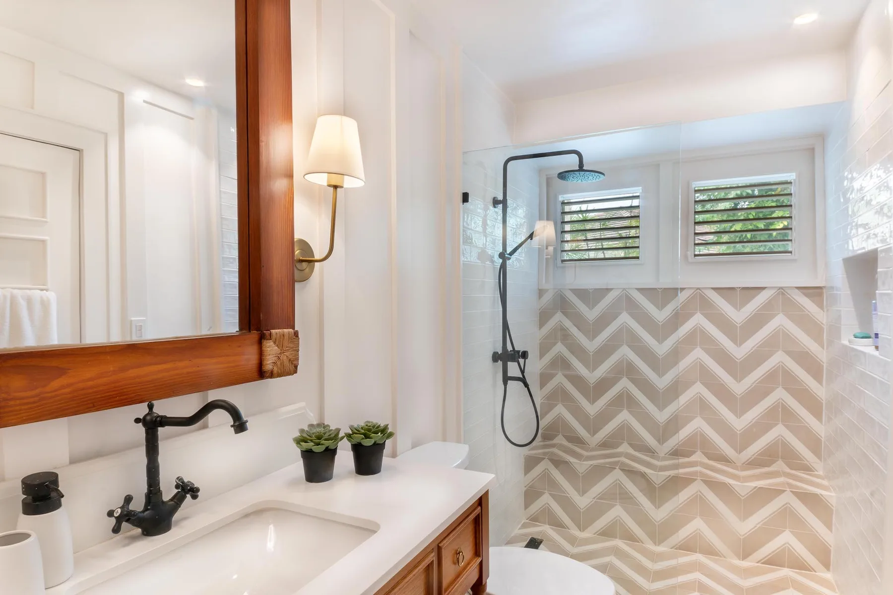 A bright bathroom with a sink, wall mirror, and walk-in shower.