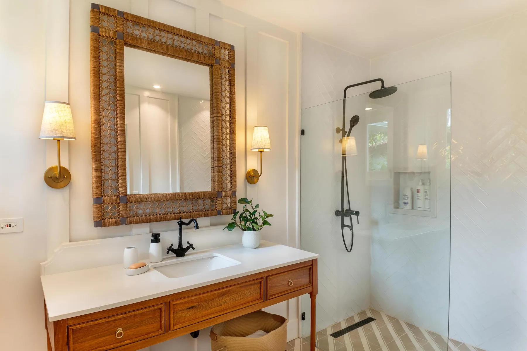 A bright bathroom with a vanity, framed mirror, and glass shower.
