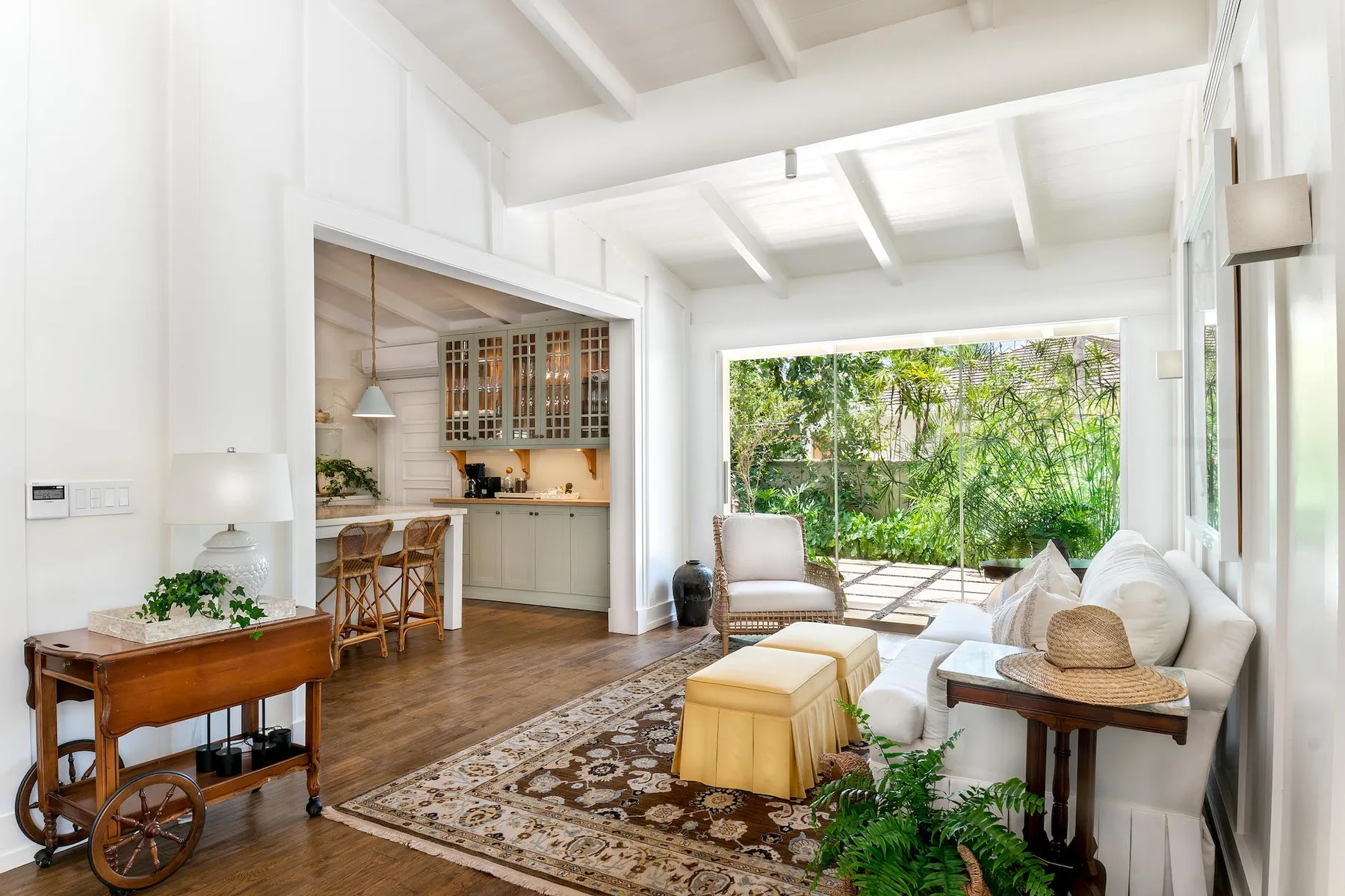 A bright living room opens onto a garden through a large glass wall.