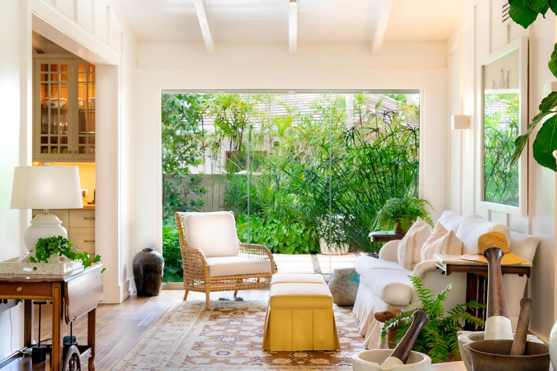 A bright living room with seating arranged around a low table, facing a garden.